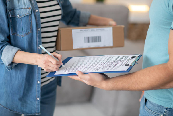 Female hands holding parcel and signing delivery documents - Photo, Image