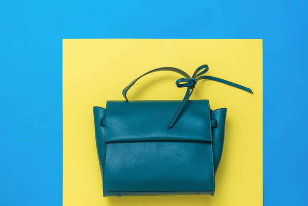 Leather women's bag in turquoise color on a yellow and blue background. The view from the top. - Photo, Image