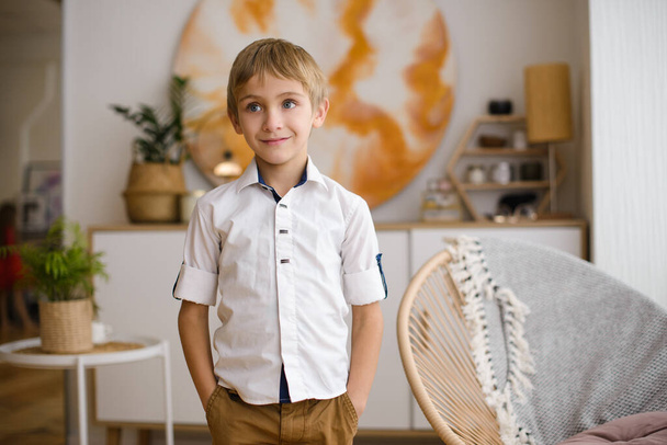 retrato de um atraente loiro elegantemente vestido menino em camisa branca no quarto brilhante
 - Foto, Imagem
