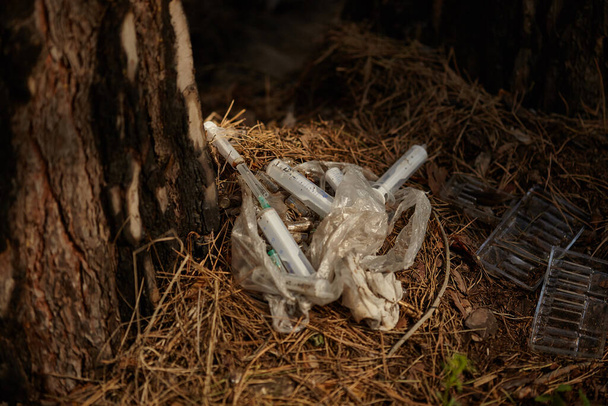 Stosuje się strzykawkę z igłą i innymi odpadami na ziemi w lesie. Strzykawki zostawiają uzależnieni. Problemy z zażywaniem narkotyków, niehigieniczne warunki i zagrożenia dla innych. - Zdjęcie, obraz