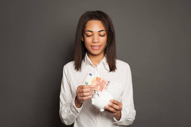 Fiksu musta nainen laittamassa rahaa pankkiin 10 euroseteliä
 - Valokuva, kuva