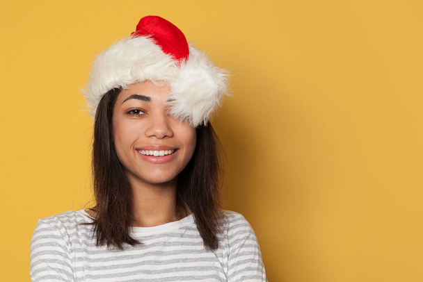 Heureuse femme noire en chapeau de Père Noël sur fond jaune
 - Photo, image