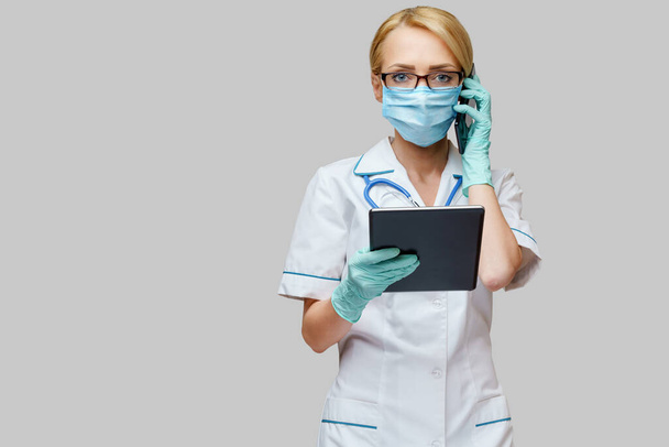 врач медсестра женщина в защитной маске и перчатках - проведение планшетный компьютер и мобильный телефон
 - Фото, изображение