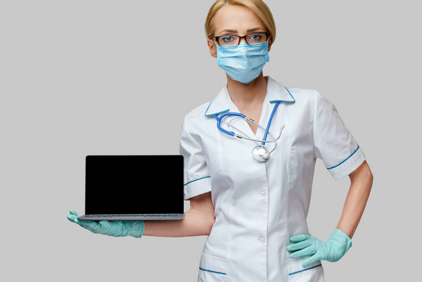 medical doctor nurse woman wearing protective mask and gloves - holding laptop - Fotoğraf, Görsel