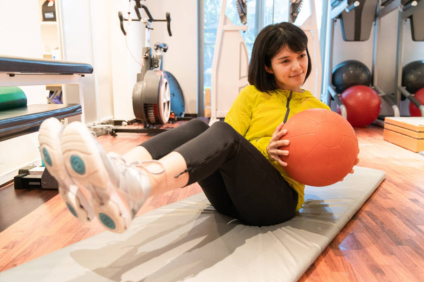 Asyalı kadın kişisel spor salonunda aletlerle kas eğitimi alıyor. - Fotoğraf, Görsel