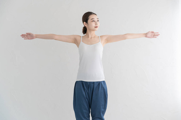 Ázsiai fiatal nő csinál enyhe testmozgás egy világos szobában - Fotó, kép