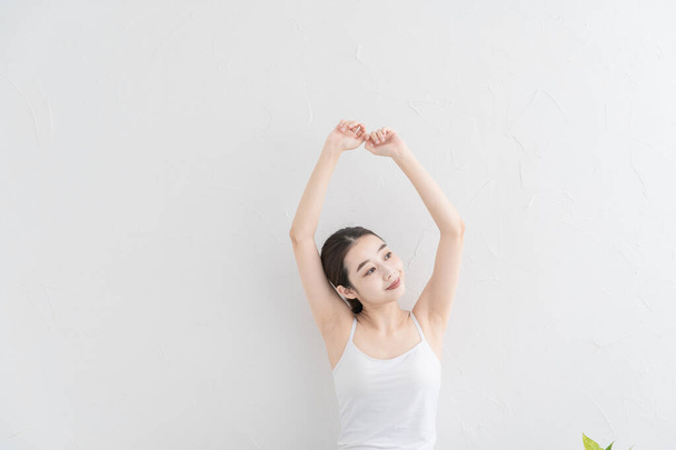 Asiática joven mujer haciendo suave ejercicio en un brillante habitación
 - Foto, imagen