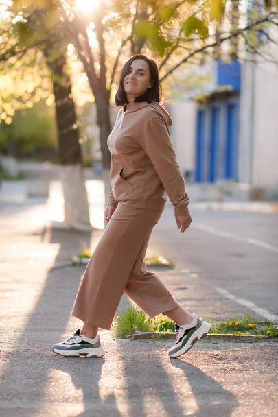 dark-haired girl walks around the city and posing in a beige suit - Foto, Imagen