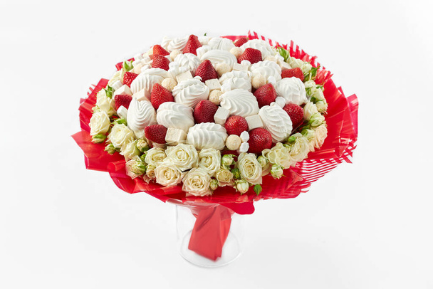 Beautiful bouquet created from white roses, marshmallows and ripe strawberries stay in vase on white background - Photo, Image