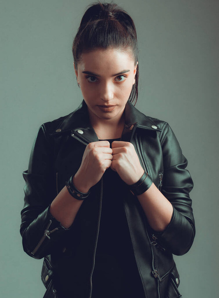 Portrait of young beautiful woman with black leather jacket ,on grey background - Fotó, kép