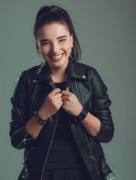 Portrait of young beautiful woman with black leather jacket,on grey background - Fotó, kép
