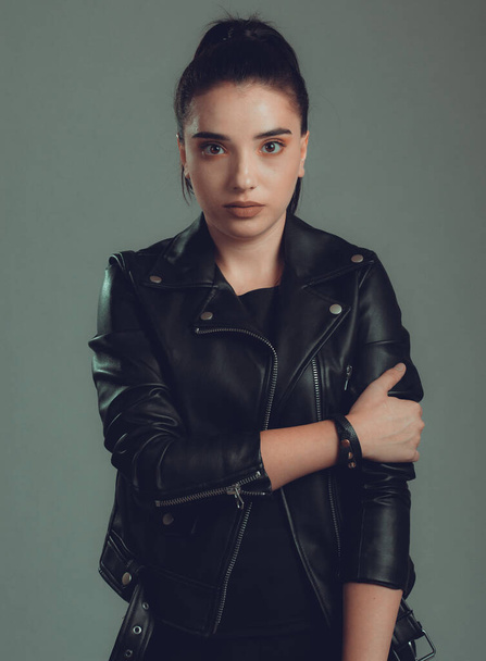 Portrait of young beautiful woman with black leather jacket,on grey background - Фото, изображение