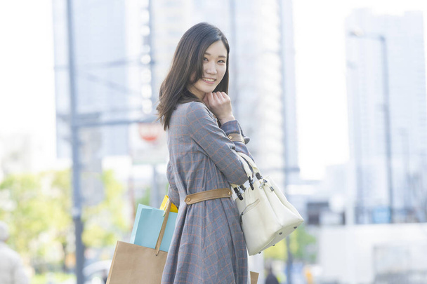 Smiling Asian young woman with lots of shopping bags of various colors - Fotoğraf, Görsel