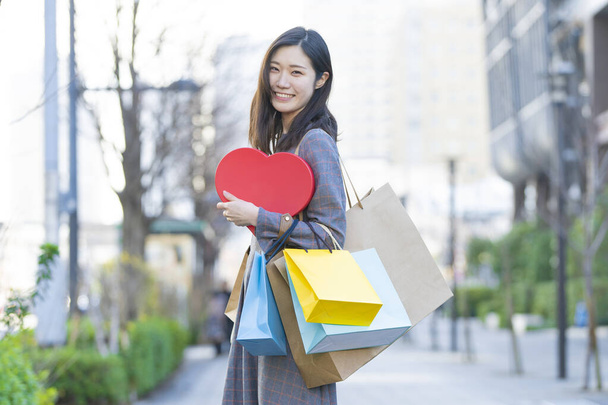Sorrindo Asiático jovem mulher com lotes de sacos de compras de várias cores
 - Foto, Imagem