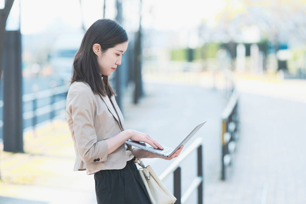 Asiatische (japanische) Büroangestellte arbeitet im Freien mit einem Laptop - Foto, Bild