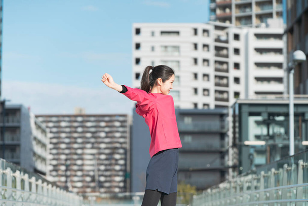 Asian young business woman exercising in the city center on a sunny day - 写真・画像