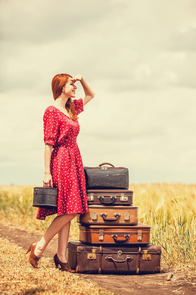 Руда дівчина з валізами на відкритому повітрі
 - Фото, зображення