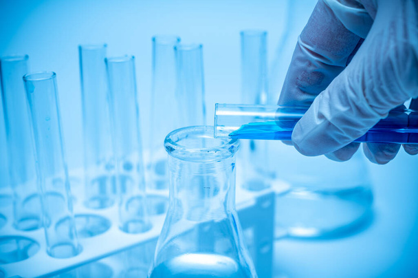 Mão de um pesquisador segurando um tubo de ensaio contendo líquido azul
. - Foto, Imagem