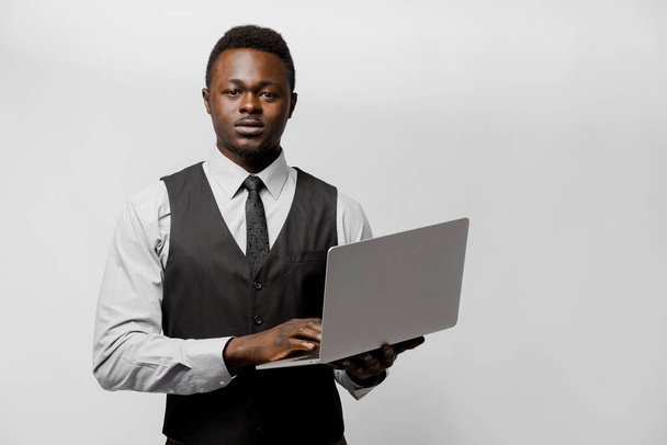 Surowy afrykański szef w ubraniach biznesowych z laptopem. Prowadzenie działalności gospodarczej on-line w domu w okresie kwarantanny covid 19 - Zdjęcie, obraz