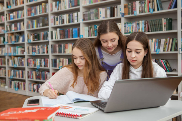 Three teenage girls studying together at school library, copy space - Zdjęcie, obraz