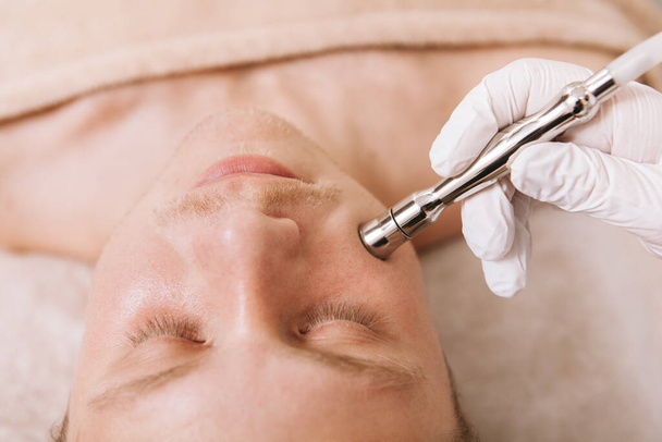 Zbliżenie na mężczyznę leczącego skórę twarzy w klinice kosmetycznej - Zdjęcie, obraz