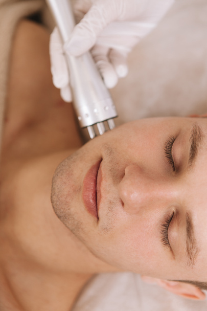 Foto vertical de un hombre guapo disfrutando del tratamiento de cuidado de la piel por un dermatólogo profesional. Concepto de elevación Rf
 - Foto, Imagen