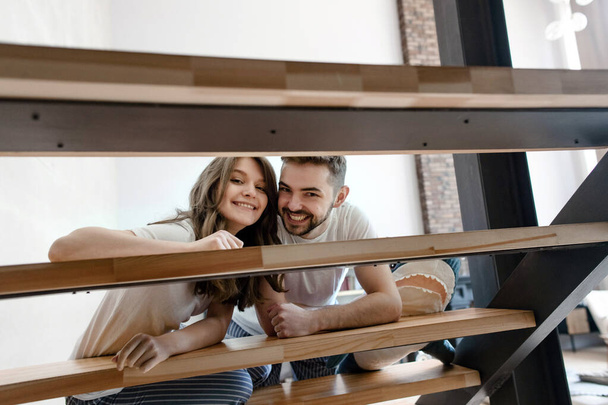 Young couple smiles and looks through the stairs in their home - Photo, image