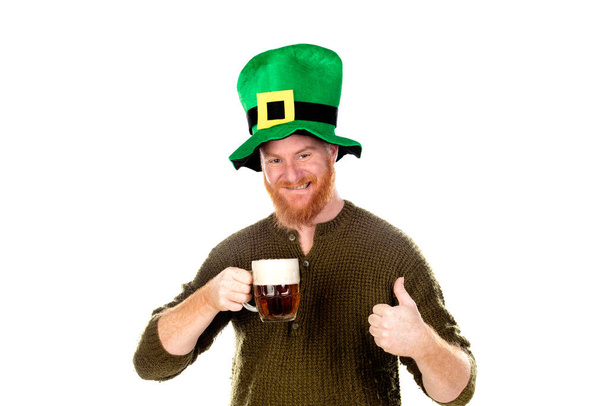 Rudowłosy facet w zielonym kapeluszu pijący piwo na białym tle - Zdjęcie, obraz