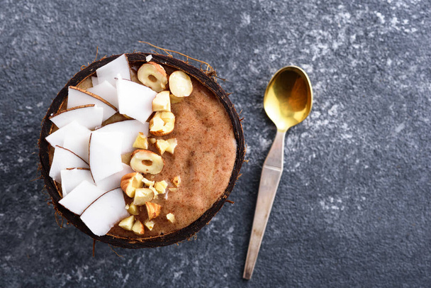 шоколадный смузи с кокосовым орехом, орехи в кокосовой миске, концепция чаши смузи, десертная ложка на сером фоне, пространство для копирования
 - Фото, изображение
