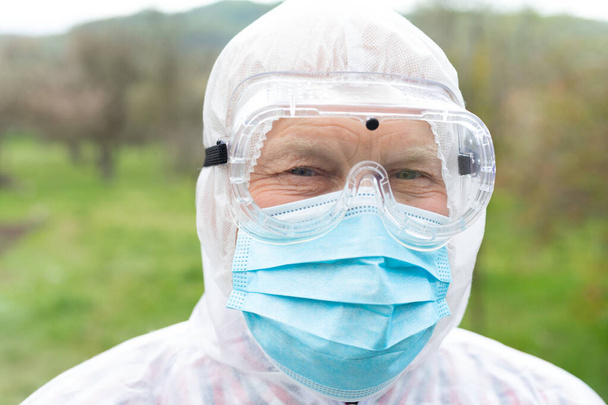 Portrait of senior man wearing hazmat suit, mask and gloves outdoor - covid-19 pandemic  - Foto, afbeelding