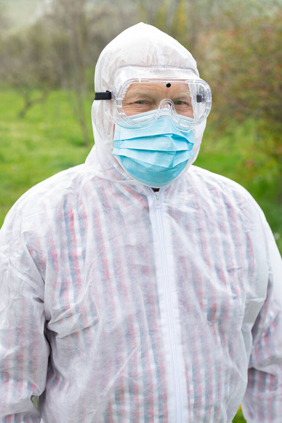 Retrato de homem sênior vestindo terno hazmat, máscara e luvas ao ar livre - covid-19 pandemia
  - Foto, Imagem