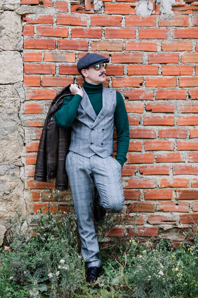 Gut gekleideter Mann in grauem Retro-Anzug, Mütze und grünem Trikot - Foto, Bild