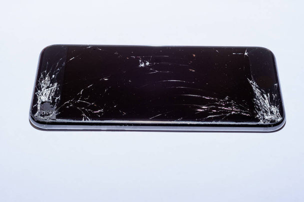View on a cracked screen of a smartphone isolated on a white background. - Photo, Image