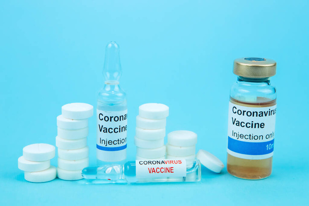 coronavirus vaccine testing. Vials with medicines, pills, syringes, thermometer, medical mask on a blue table. a cure for seasonal flu and the common cold. Means for the treatment of covid-19 - Photo, image