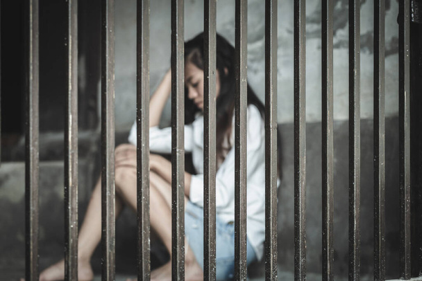 Het hopeloze slavin meisje zit in een cel. Vrouwelijk geweld en misbruikt concept, Gevangenis, Vrouwelijke gevangene, Mensenhandel Concept, Internationale Vrouwendag. - Foto, afbeelding