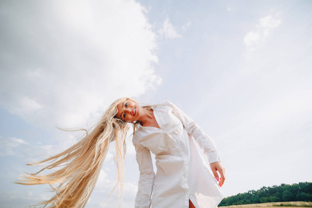 bella donna con i capelli lunghi biondi in un campo al tramonto. estate, agricoltura, natura e aria fresca. soleggiato
. - Foto, immagini