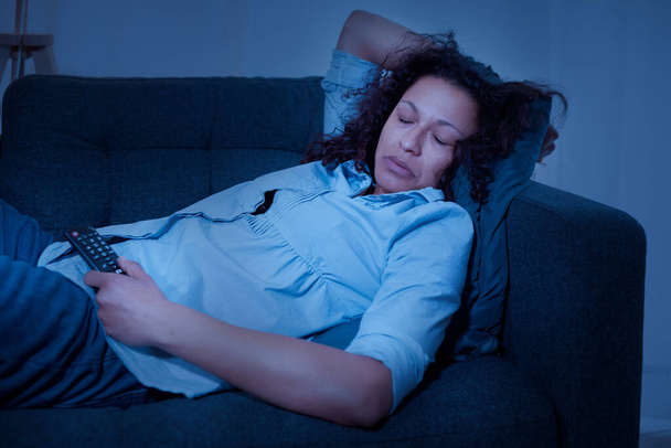 Μαύρη κουρασμένη γυναίκα χαλαρώνει στο σπίτι βλέποντας τηλεόραση - Φωτογραφία, εικόνα