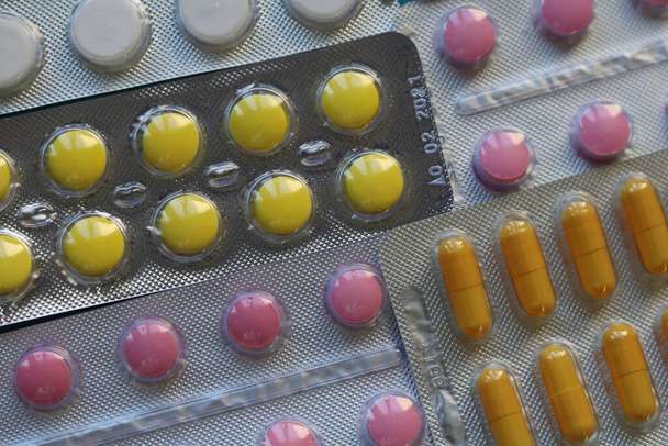 Többszínű tabletta buborékcsomagolásban: sárga, rózsaszín, narancs. - Fotó, kép