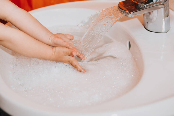 Banyoda ellerini yıkayan tatlı küçük bir kız. Grip ve covid-19 gibi enfeksiyon ve virüslerin önlenmesini gösteren hijyen kavramı - Fotoğraf, Görsel