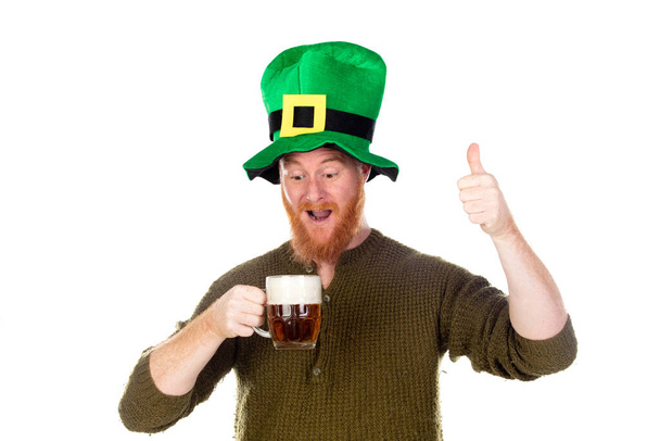 Roodharige man met een grote groene hoed drinkt een biertje geïsoleerd op een witte rug - Foto, afbeelding