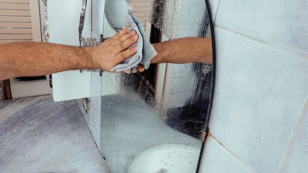 Vrolijke man schoonmaken badkamer spiegel. - Foto, afbeelding