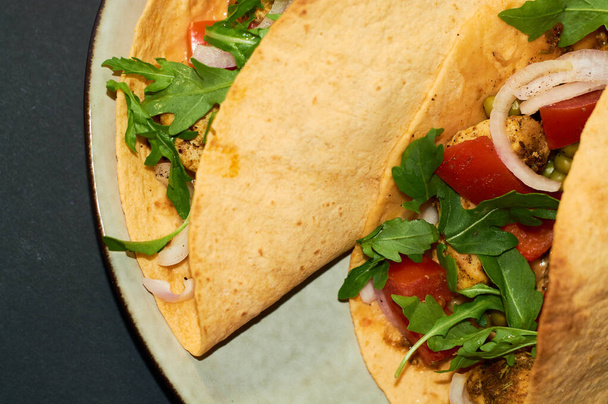 Plaat met Mexicaanse keuken, grote taco 's met groenten en vlees op zwarte achtergrond. - Foto, afbeelding