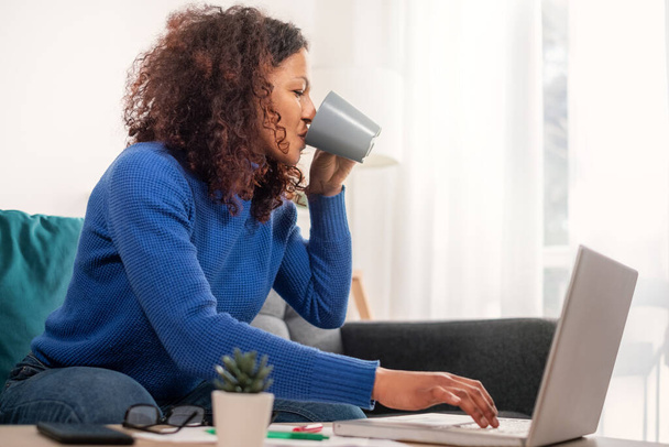 Одна черная женщина работает из дома с помощью ноутбука
 - Фото, изображение