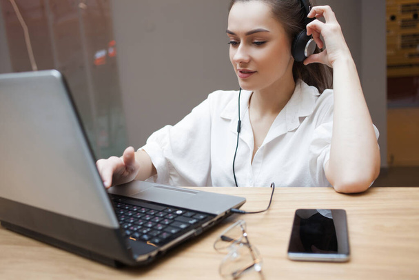 Online interview, business or personal conversation online, concept. Young attractive woman in headphones - Fotoğraf, Görsel