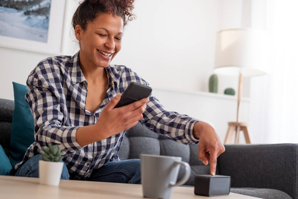 gelukkig zwart vrouw met behulp van smart speaker thuis - Foto, afbeelding