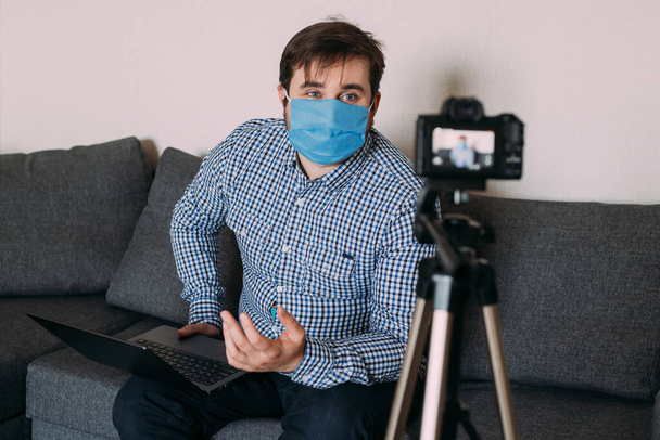 Man vlogger next to video camera at home while stay home on coronavirus quarantine. Man recording vlog message at home for internet channel - Foto, afbeelding
