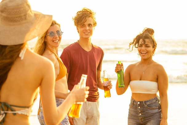 happy international friends drinking smoothie juice from glass bottle on the beach - Фото, зображення
