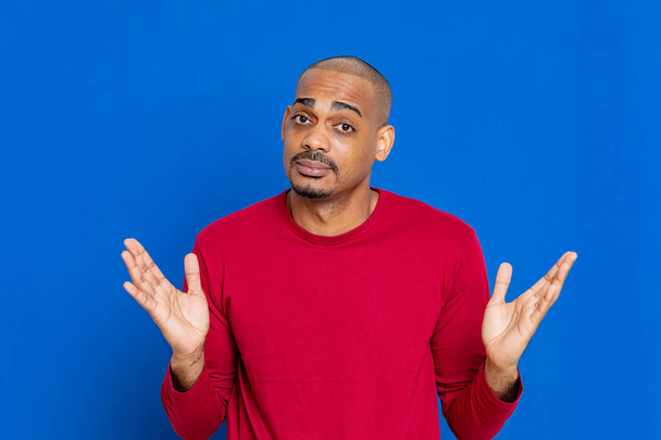 Afrikaanse man met rood T-shirt op een blauwe achtergrond - Foto, afbeelding
