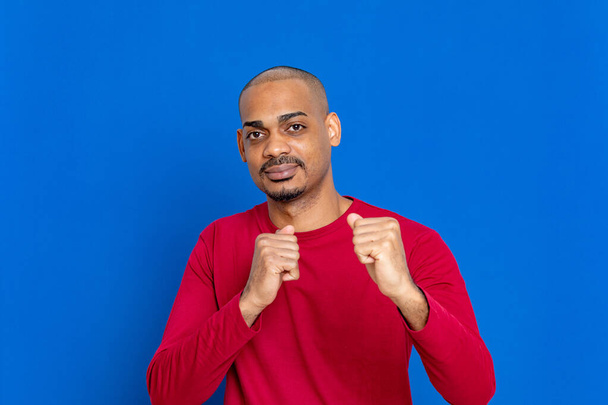 Chico africano con camiseta roja sobre fondo azul
 - Foto, imagen