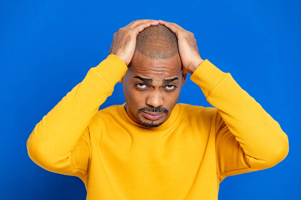 African guy with a yellow jersey on a blue background - Foto, afbeelding